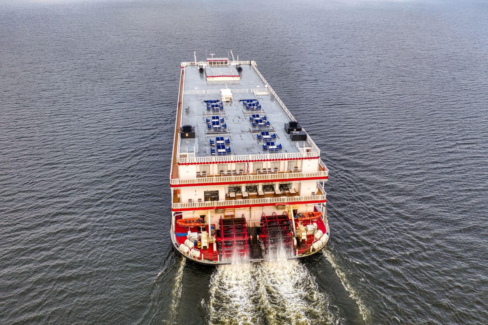 Aerial view of a white sternwheel paddlewheeler with a red wheel churning up the wide Mississippi at Lake Pepin, Minnesota, on one of the Mississippi paddlewheel cruises