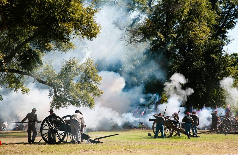 Re-enactors in period dress firing Civil War cannon in a wooded park, the kind of living history guests meet along the Mississippi