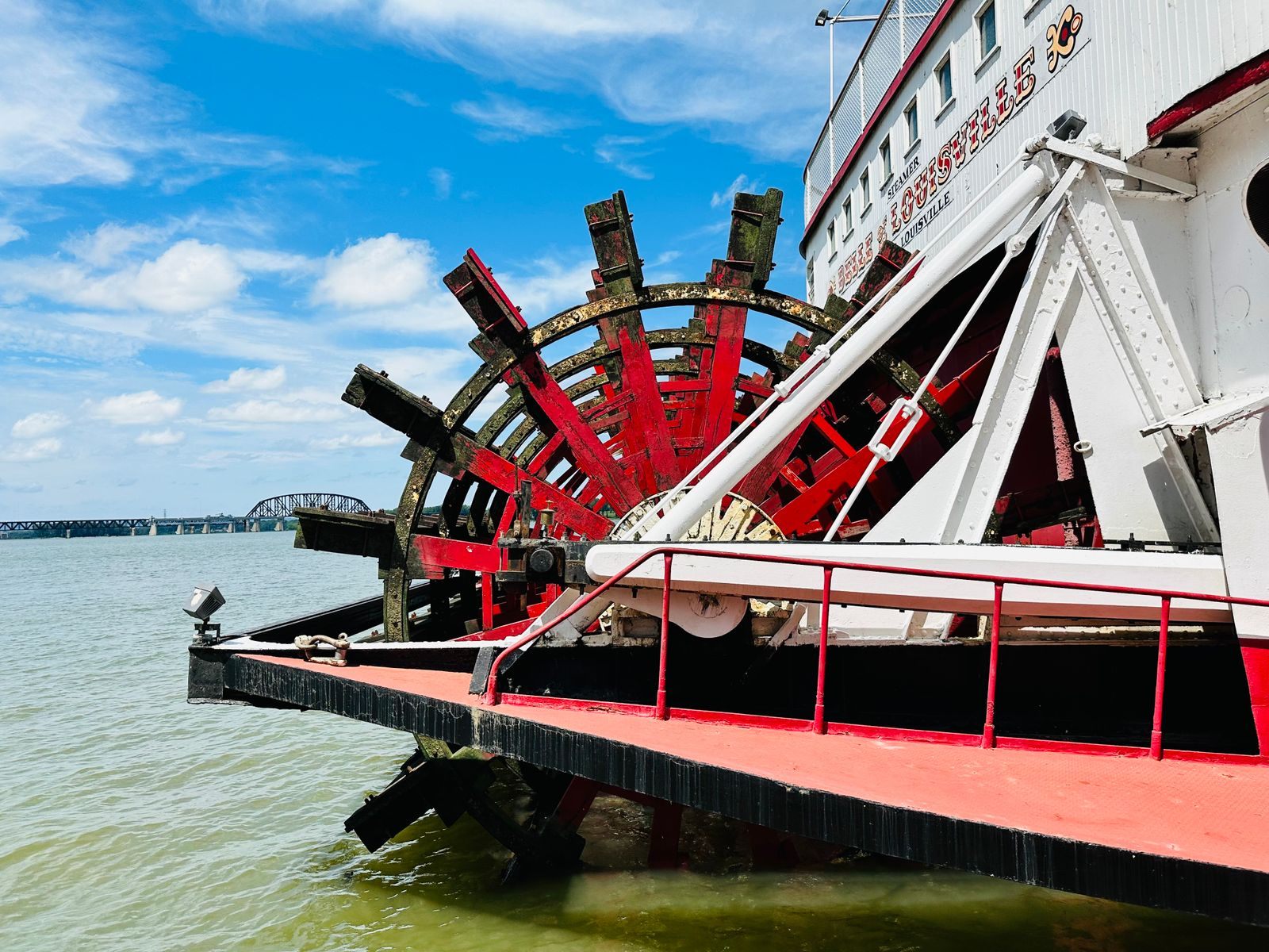 Close-up of a red paddle wheel at the stern of a classic riverboat, the signature of paddle wheel boat cruises